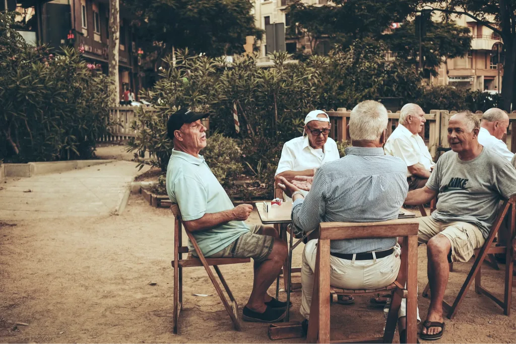 Older men sitting together outdoors at a cafe, talking and enjoying each other's company