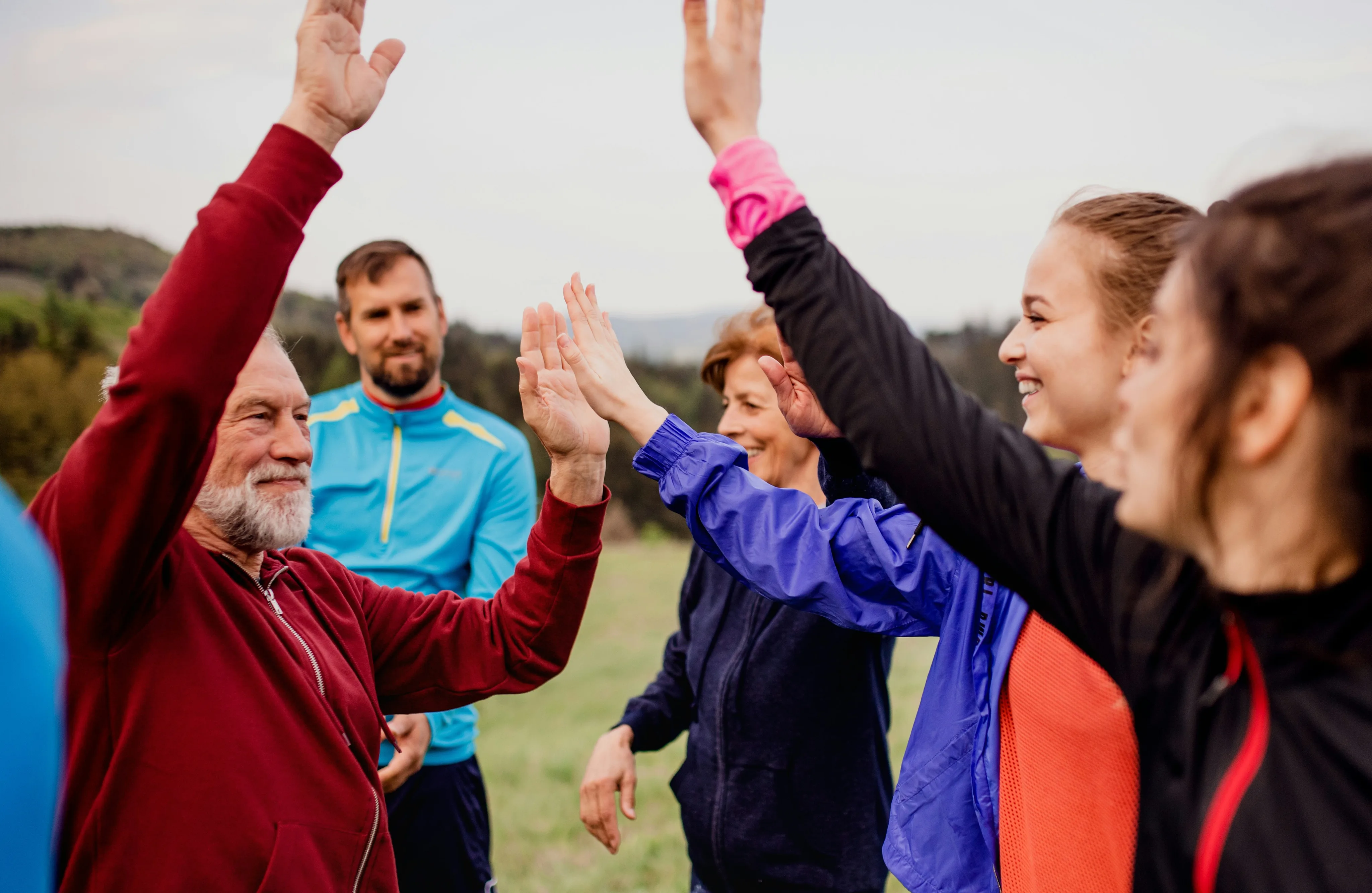 Group of people cheering and high-fiving outdoors